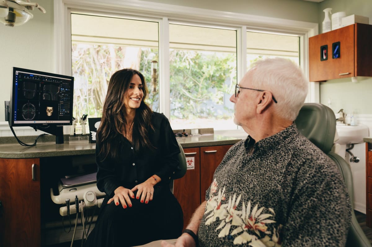 Dentist consulting with patient in modern dental office with large windows