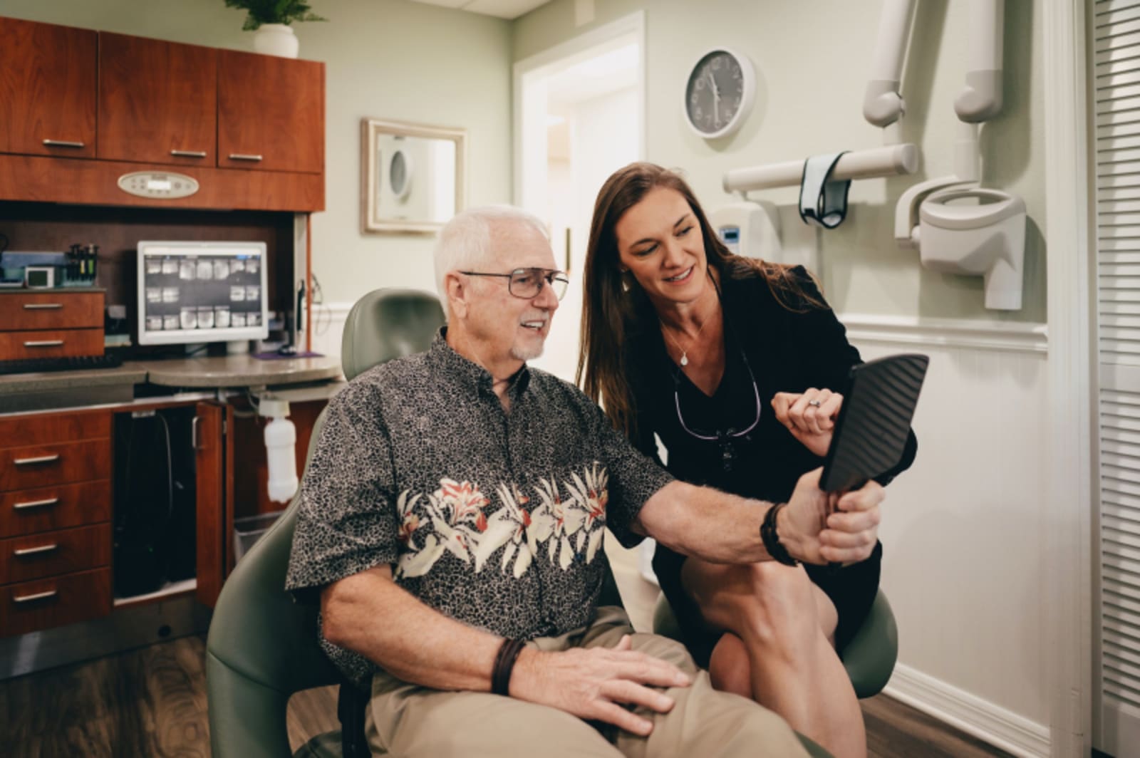 Dentist examining patient in clinical setting with equipment visible