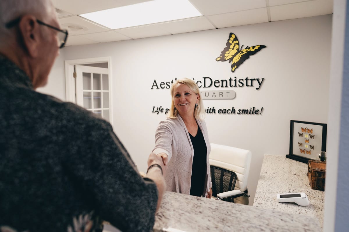 Dentist consulting with patient at front desk in modern dental office.