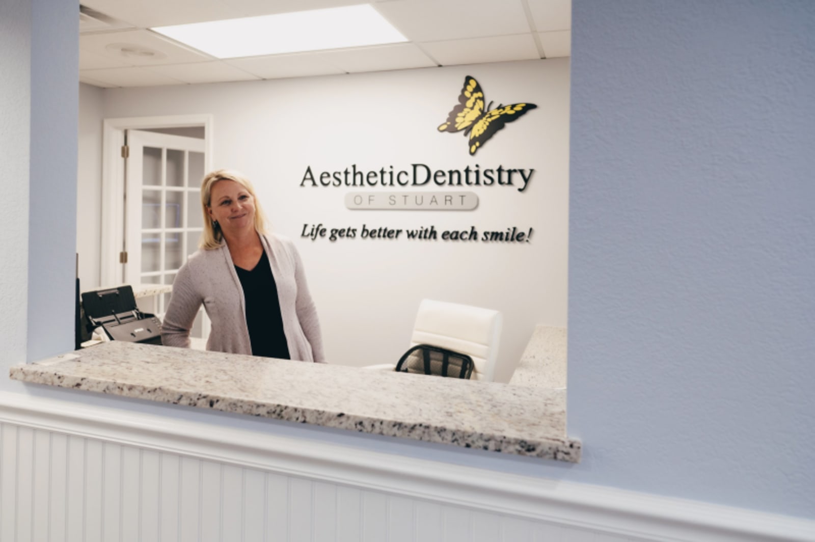 Dental professional consulting with patient at reception desk in modern office setting.