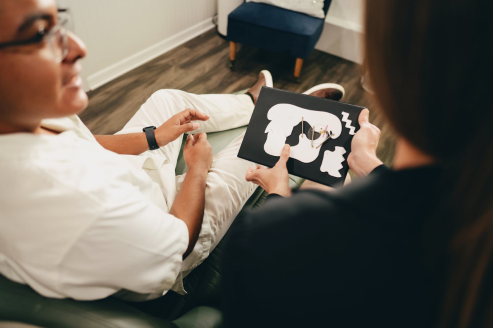 Dentist showing patient myofunctional therapy diagram on tablet during consultation.