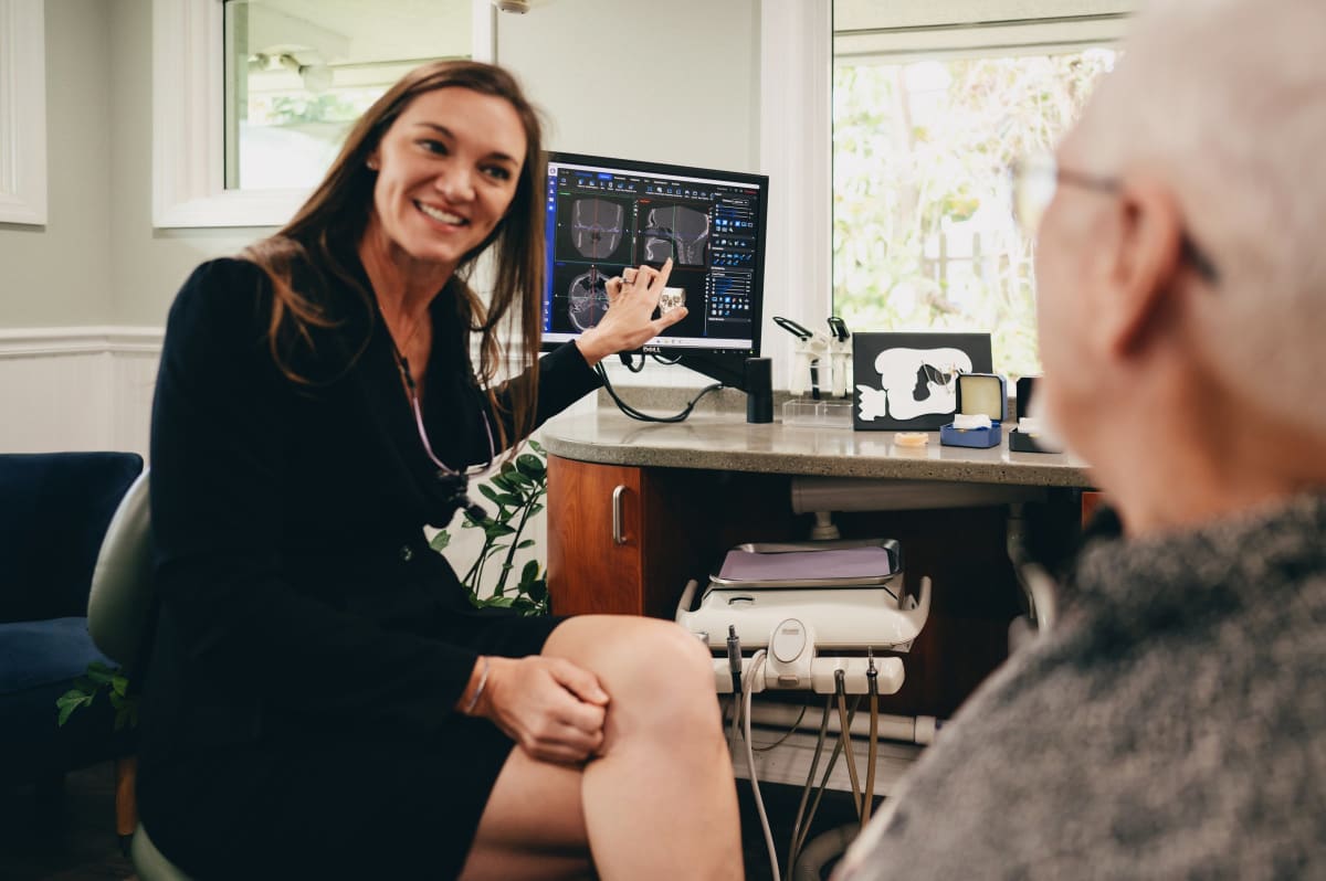 Female dentist discussing sleep apnea diagnosis with male patient in clinical setting