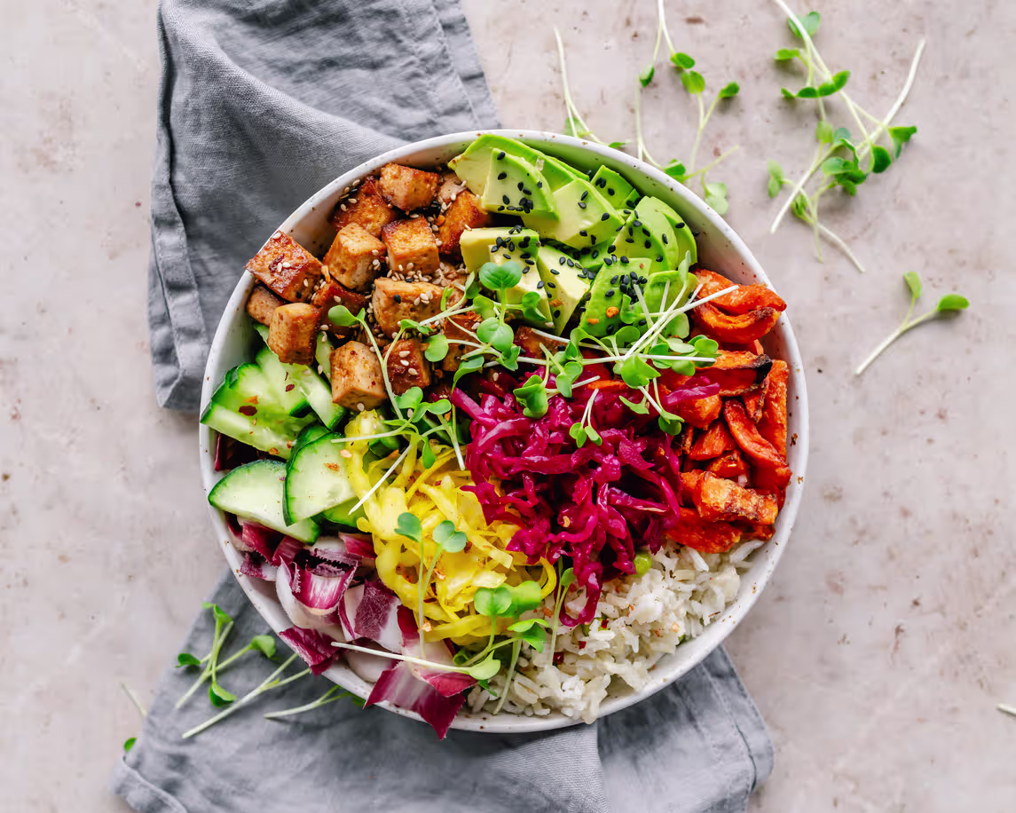 Overhead view of a colorful vegan buddha bowl with roasted tofu and rainbow veggies