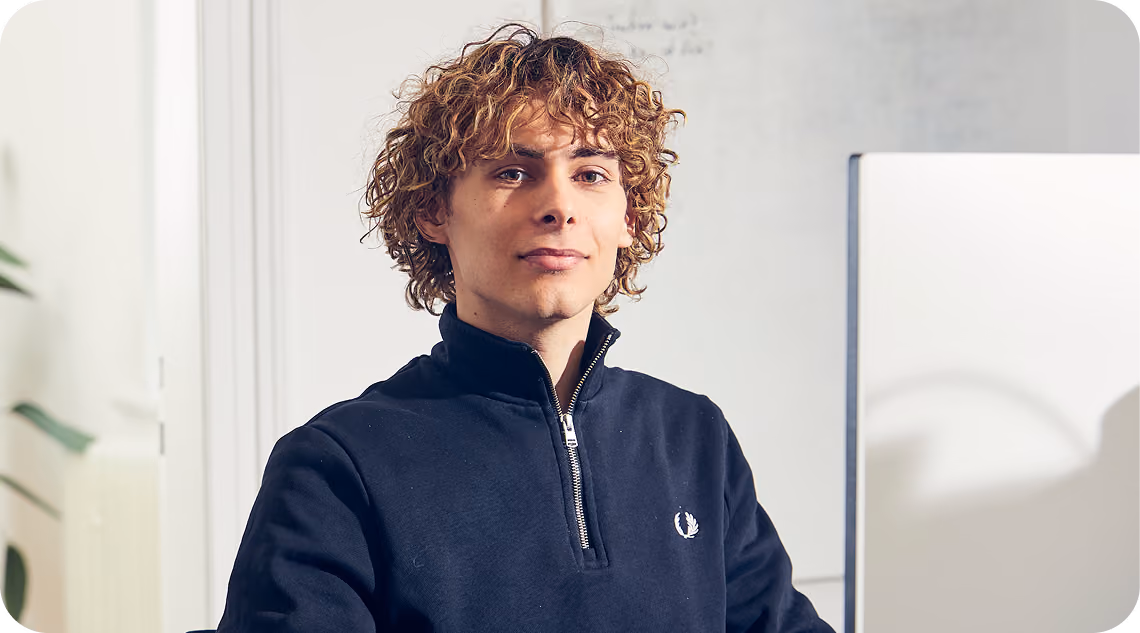 Emil, Mitgründer von THEFABERS, sitzt an seinem Arbeitsplatz im Büro vor einem Whiteboard