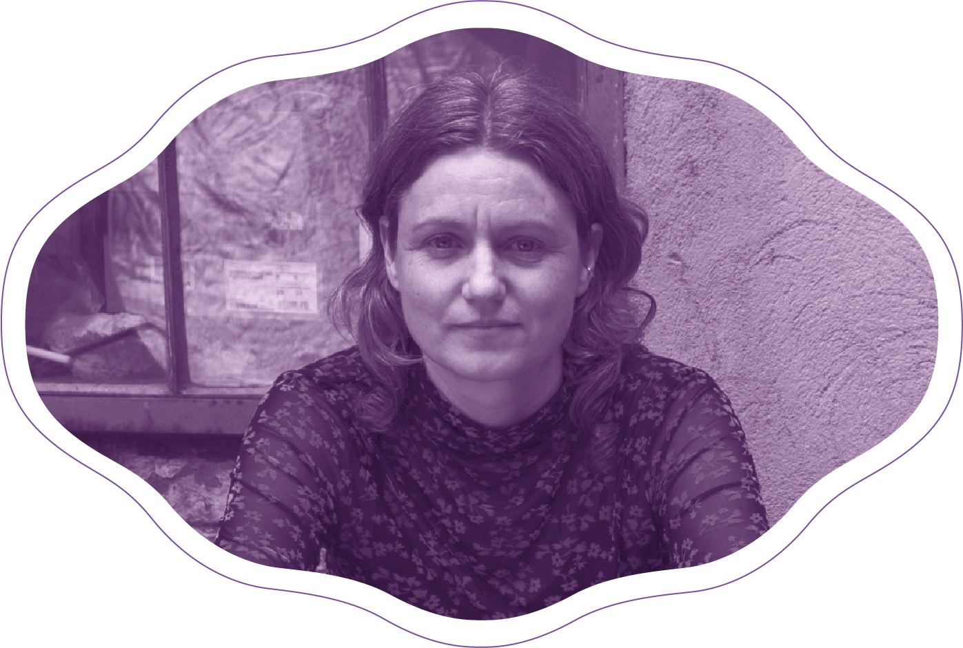 Woman with long dark hair, wearing a dark shirt, sitting in front of a bookshelf.