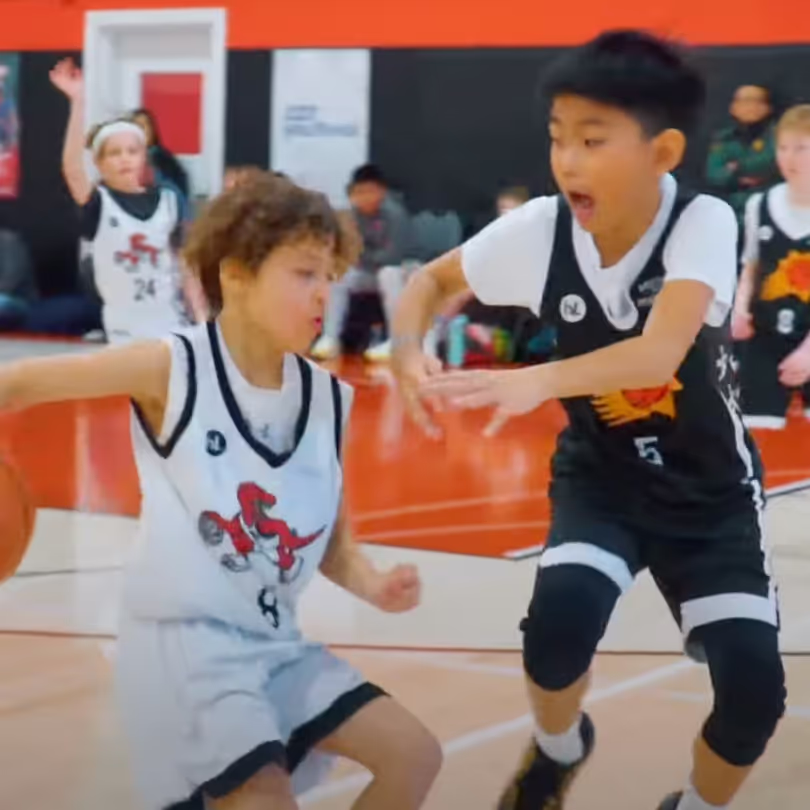 A basketball player crossing over his defender