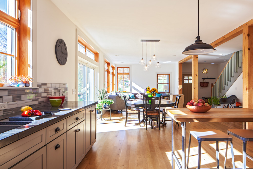 Bright, open-concept kitchen and living area with wooden beams and large windows