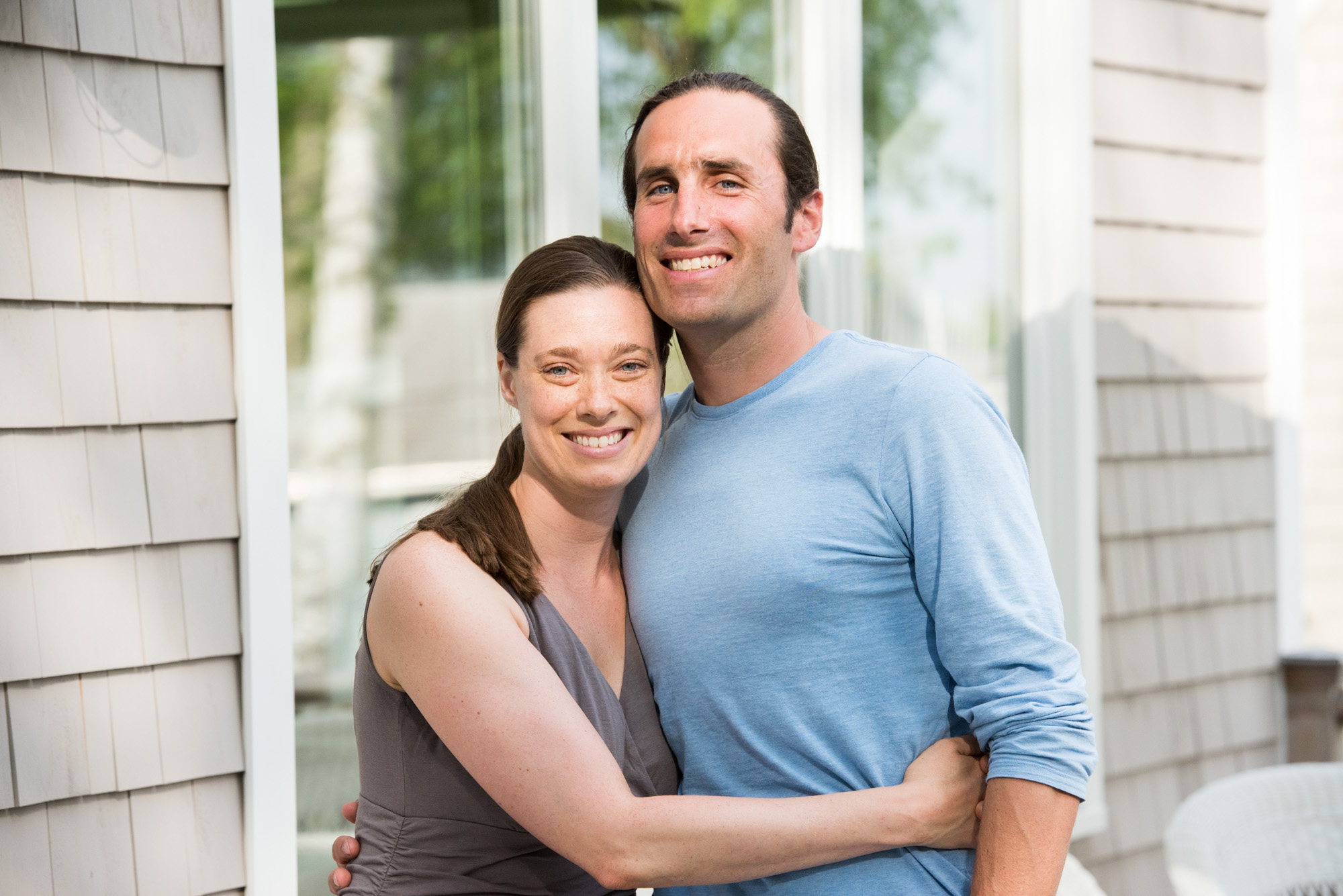 Smiling couple embracing in front of white house exterior