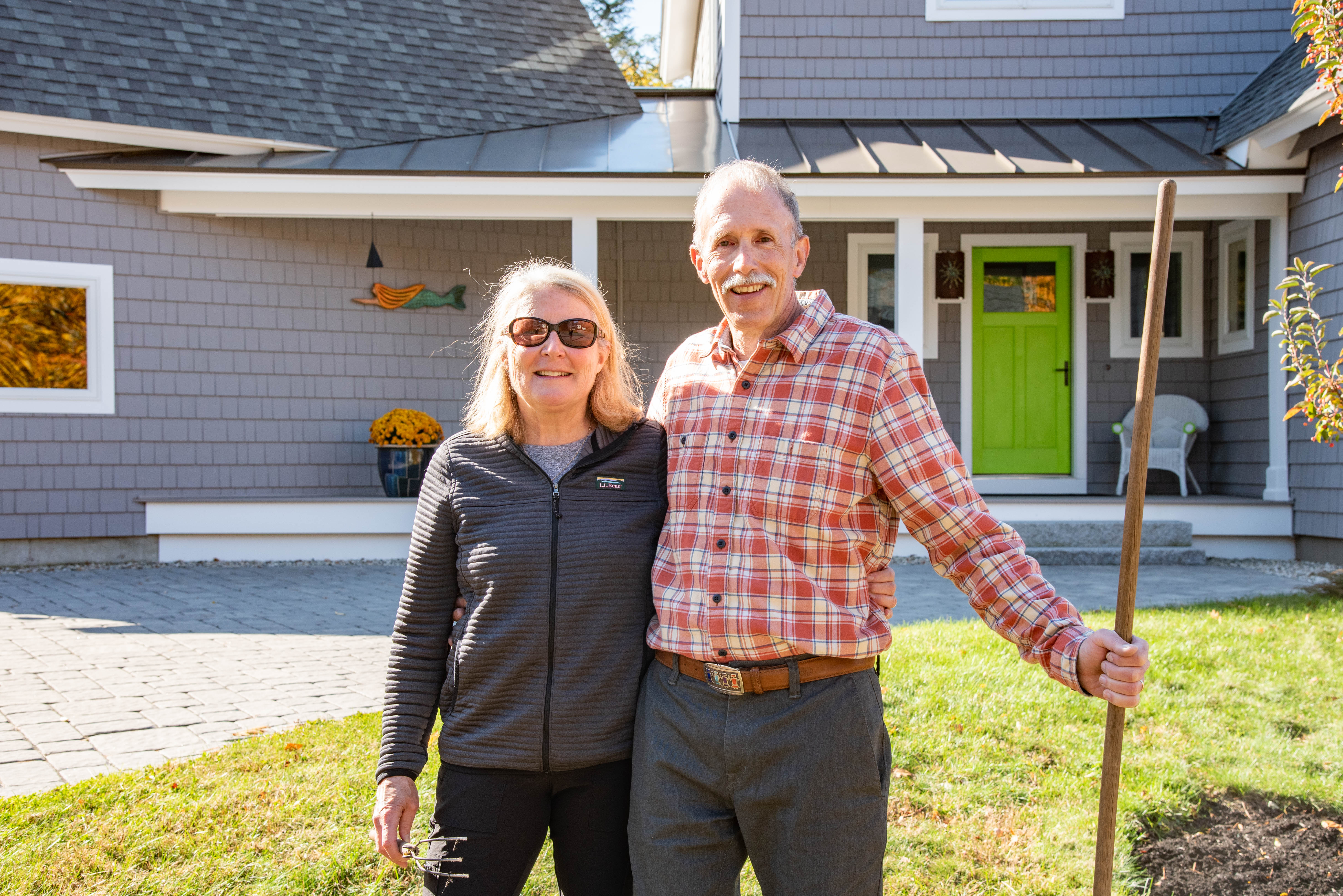 Older couple standing together in front of their home with green door