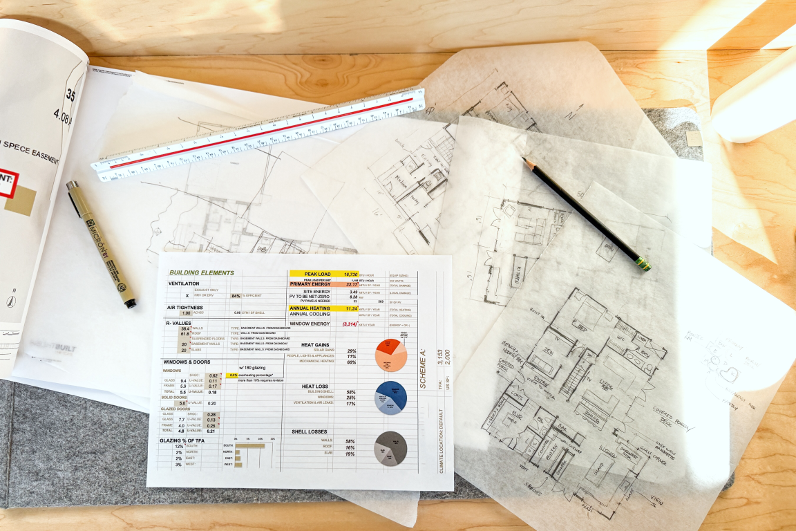 Architectural blueprints, ruler, and energy performance chart on wooden surface