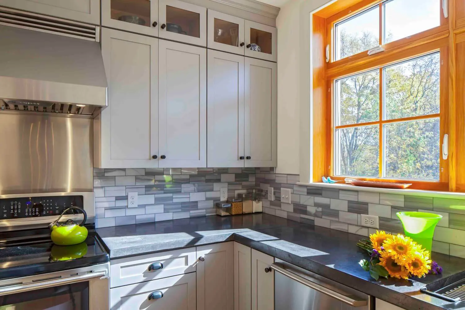 Modern white kitchen with sunflowers, bright windows, and stainless steel appliances