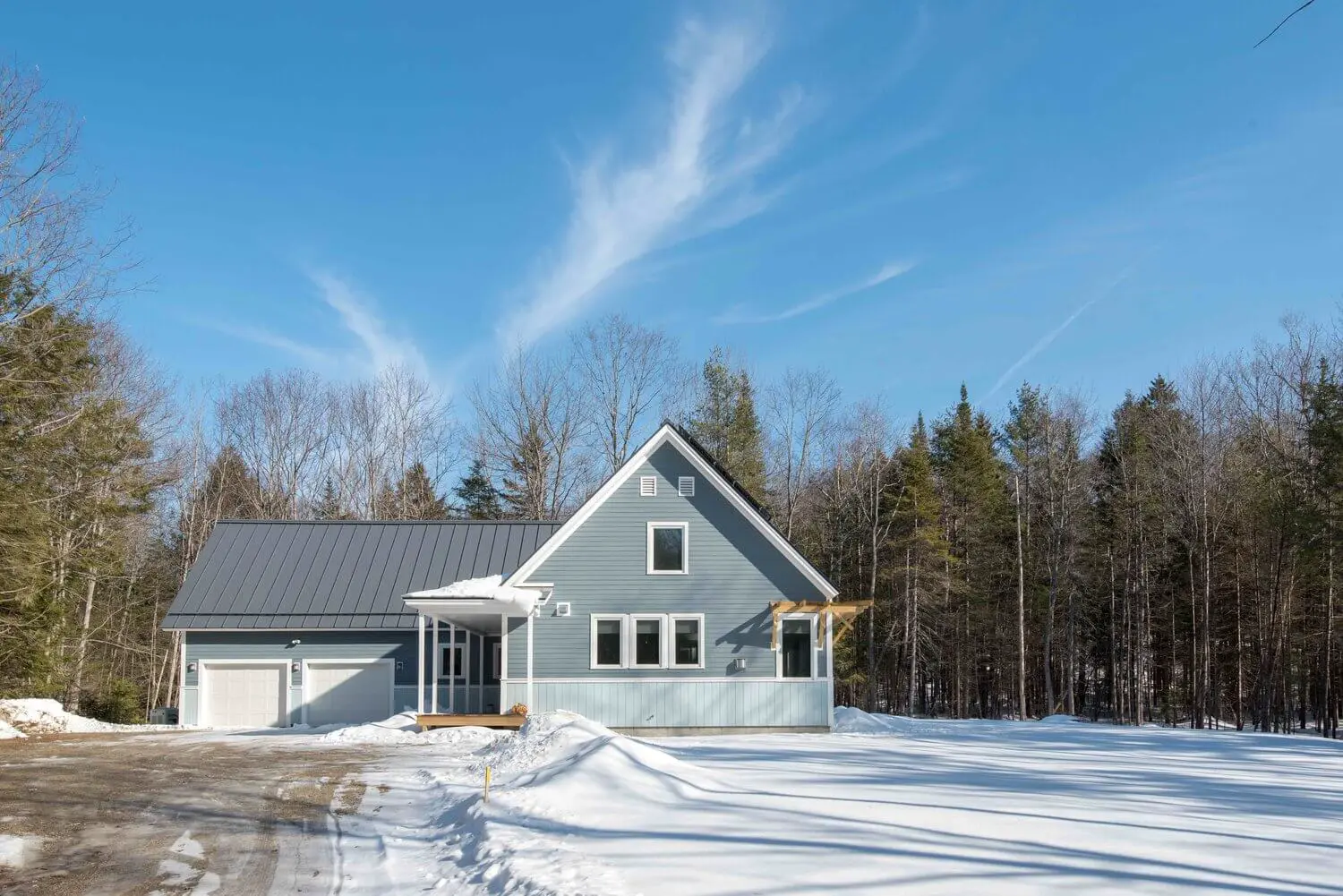 Gray house with snow-covered yard on a bright winter day
