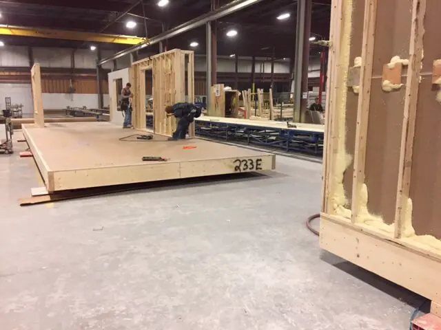 Construction workers building wooden wall frames in an indoor workshop