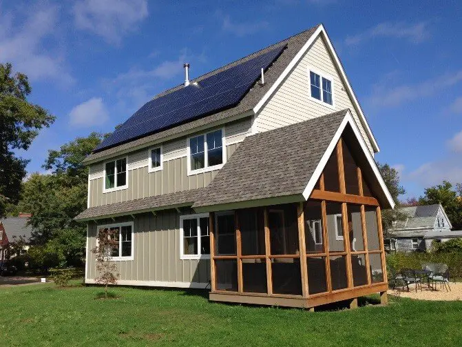 Modern house with solar panels and screened porch on green lawn