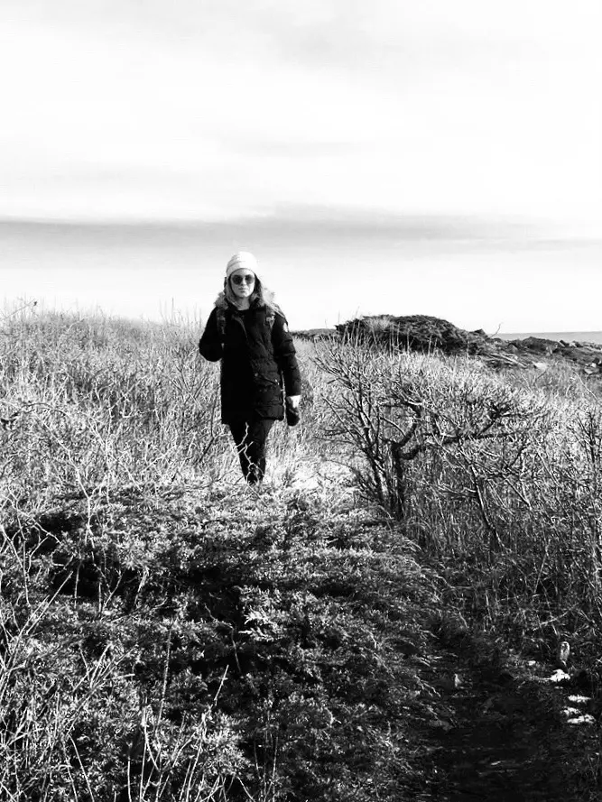 Person walking along rocky coastal path on a cloudy winter day