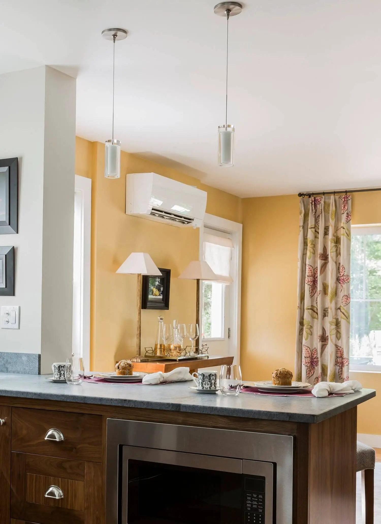 Kitchen counter with table setting, warm yellow walls, pendant lights