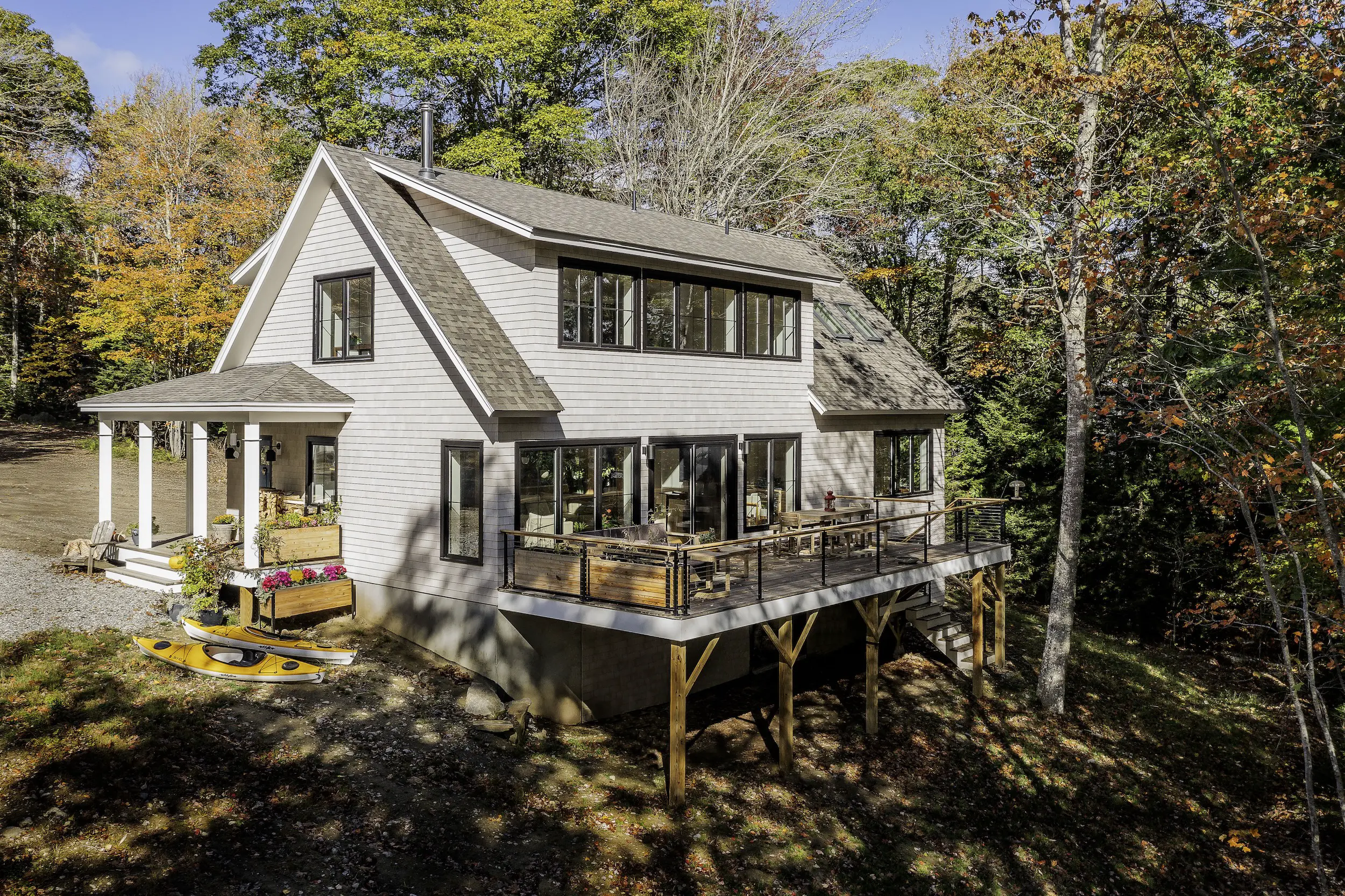 Modern wooden cabin on stilts with large deck in autumn forest