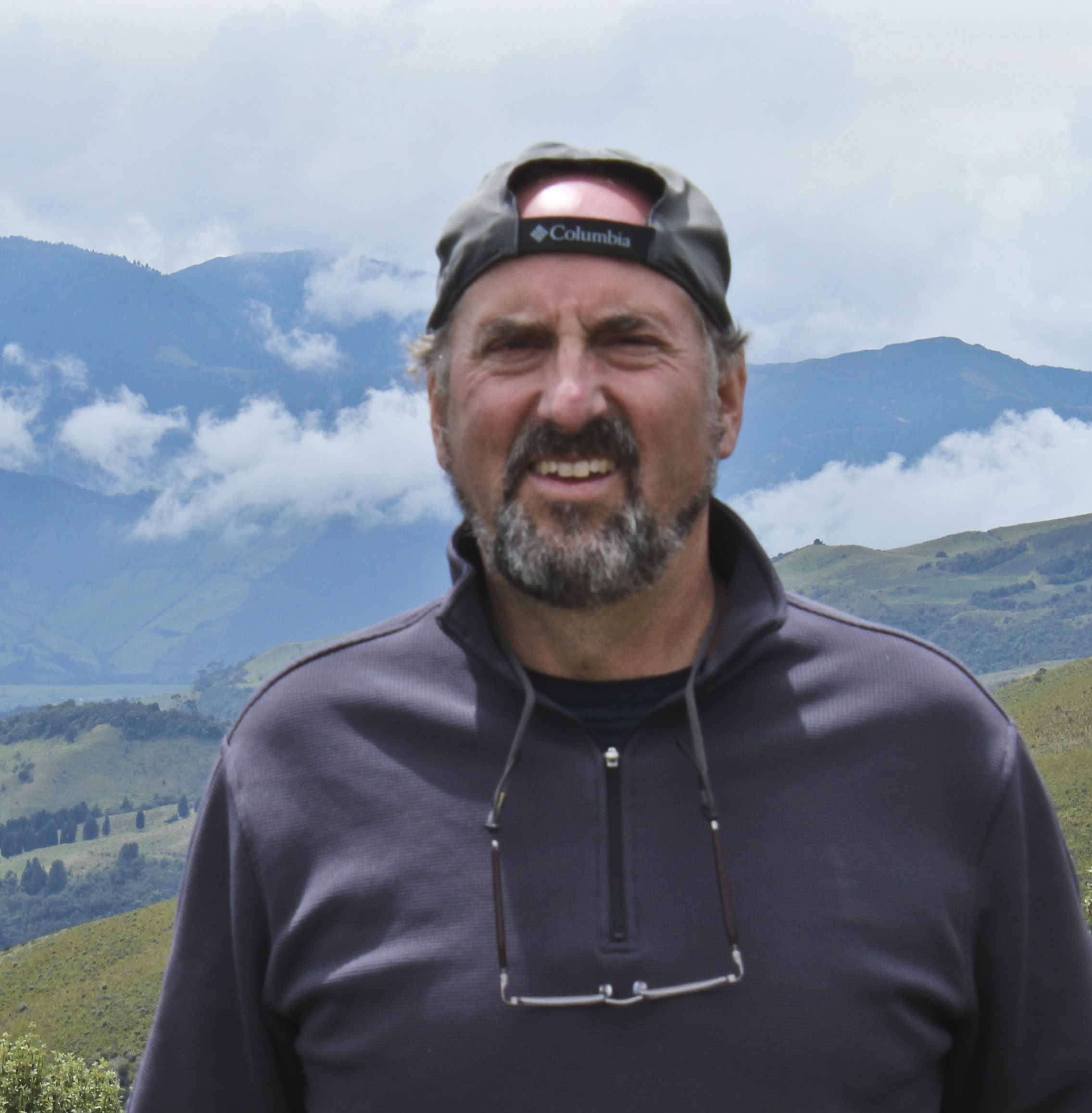 Smiling hiker in Columbia cap standing in mountainous landscape