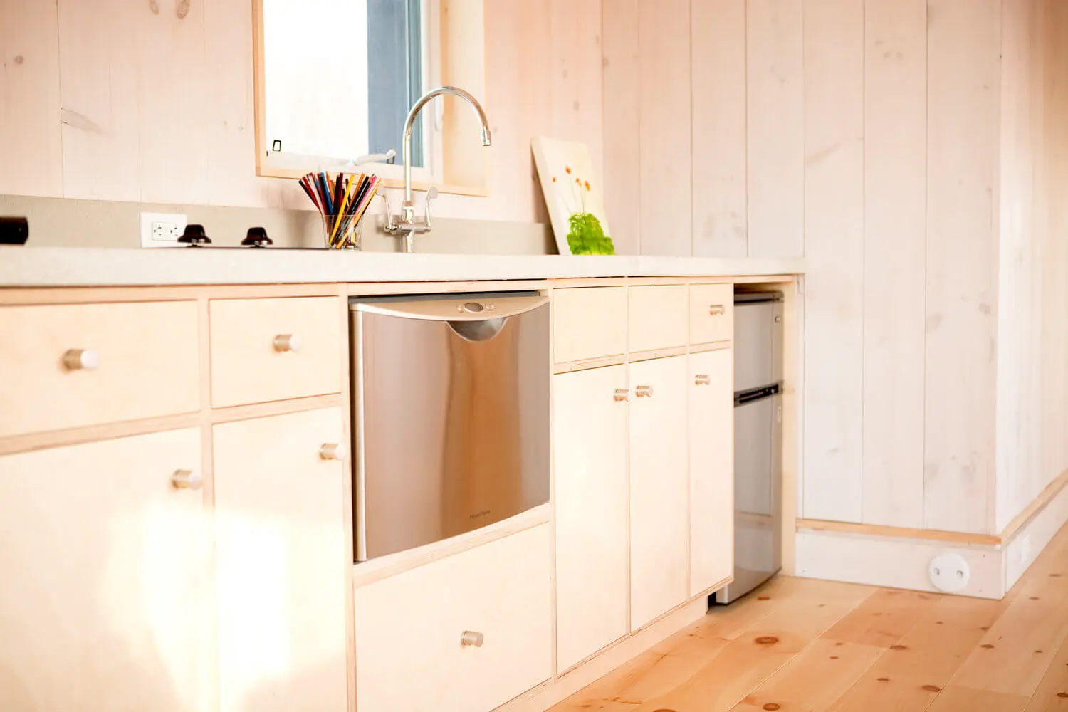 White kitchen cabinets with stainless steel dishwasher and colorful pencils