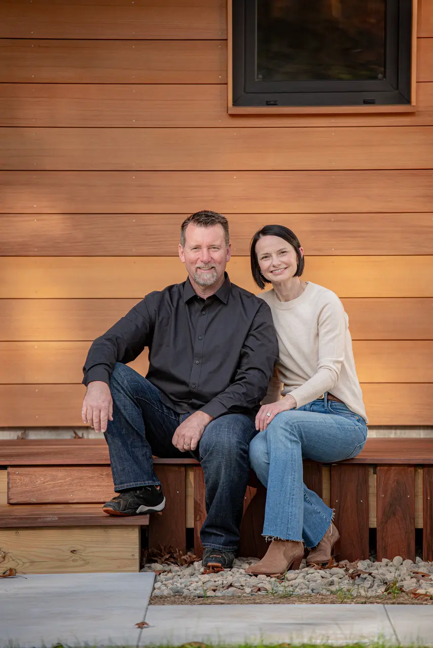 Middle-aged couple sitting together on wooden bench outside modern building