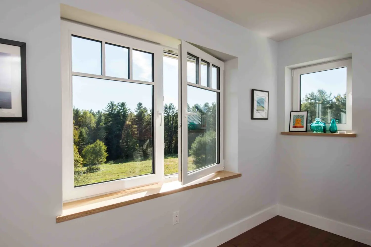 Modern white room with large windows overlooking pine forest landscape