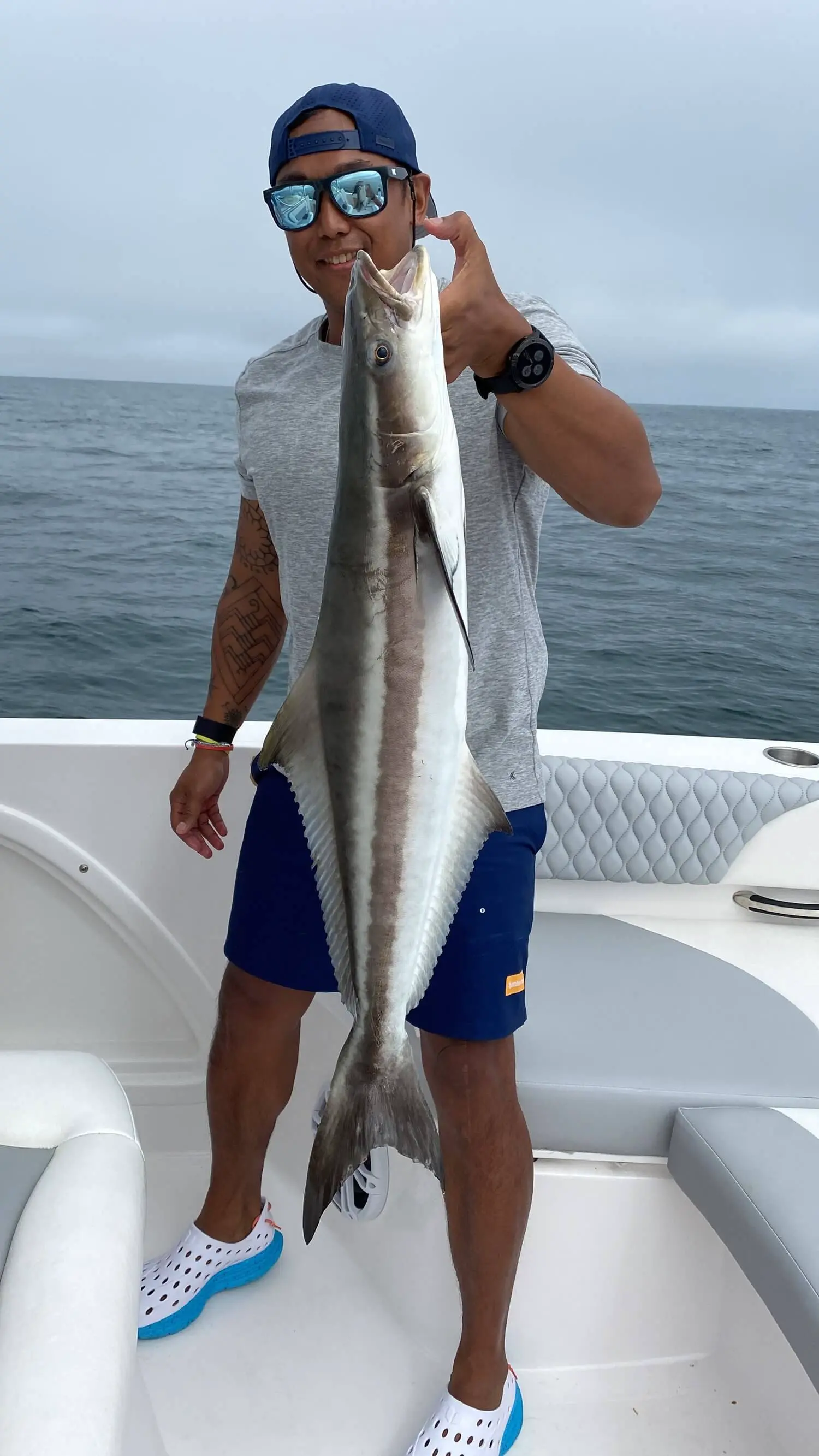Fisherman holding a large silver fish on a boat at sea