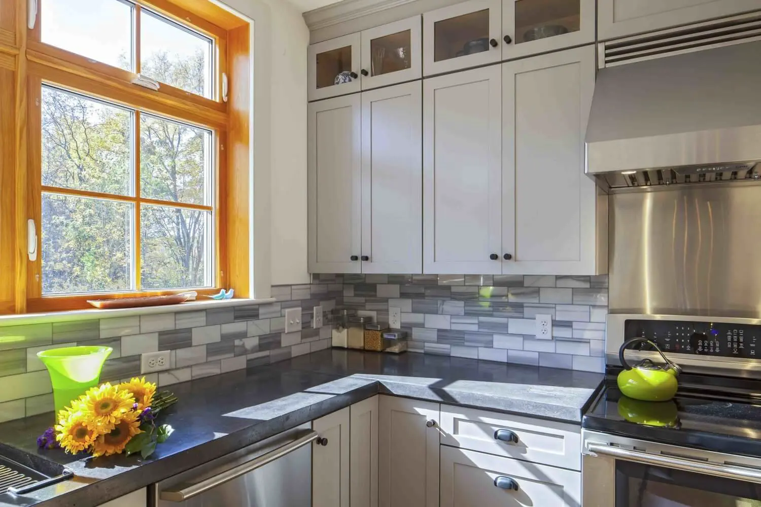 Modern kitchen with white cabinets, gray backsplash, and sunflowers