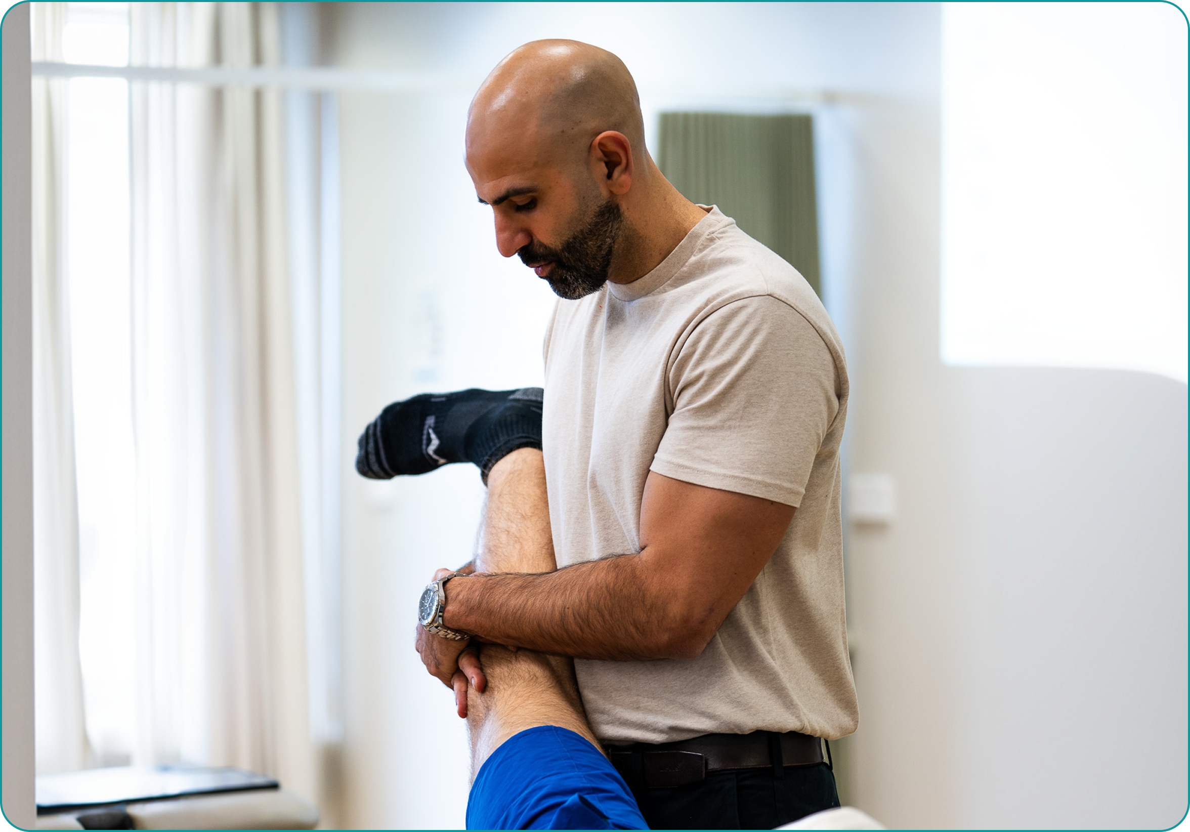 Physiotherapist performing a hip mobility stretch on a patient.