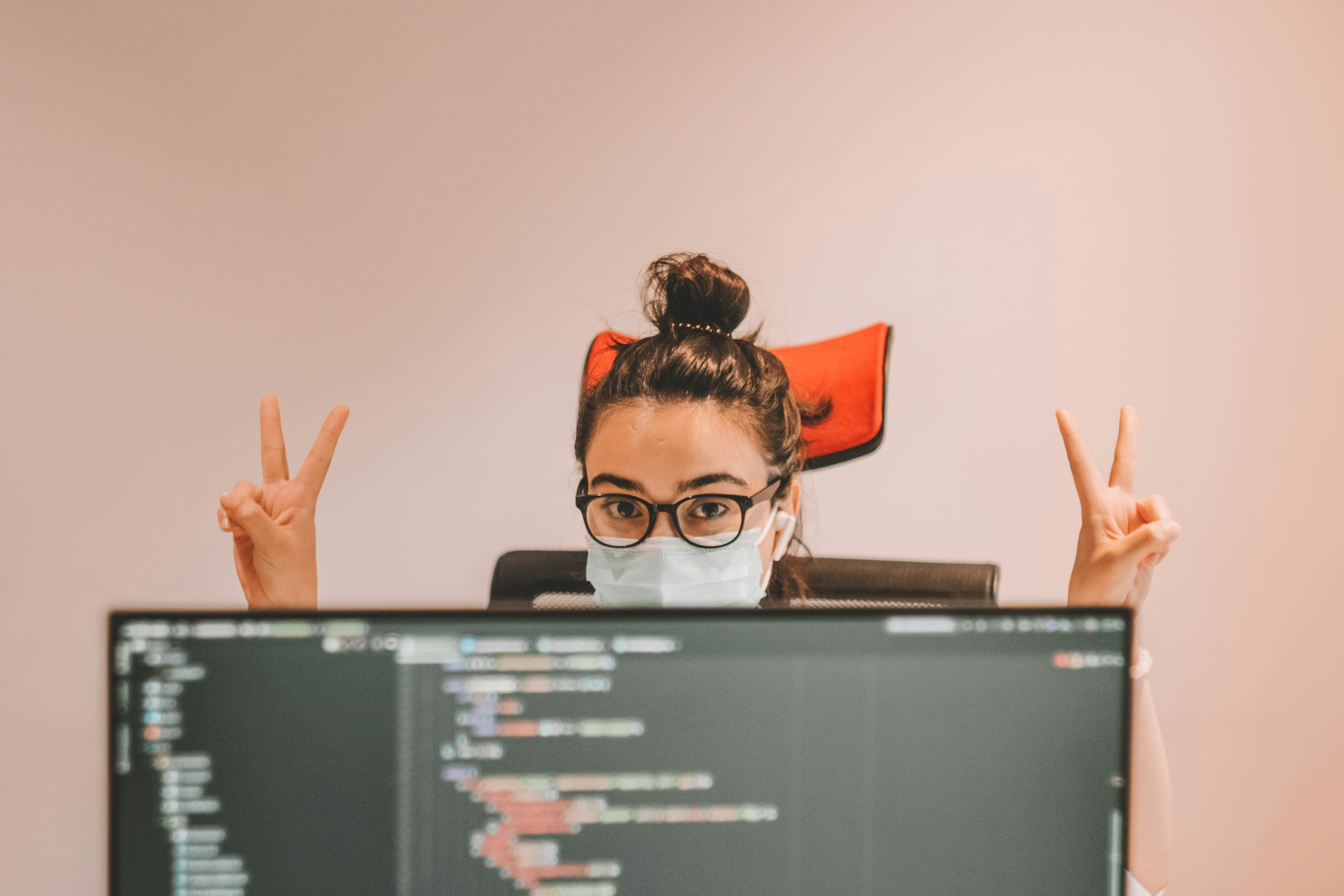 Girl giving up victory igns while sitting beside the computer running Terraform Test