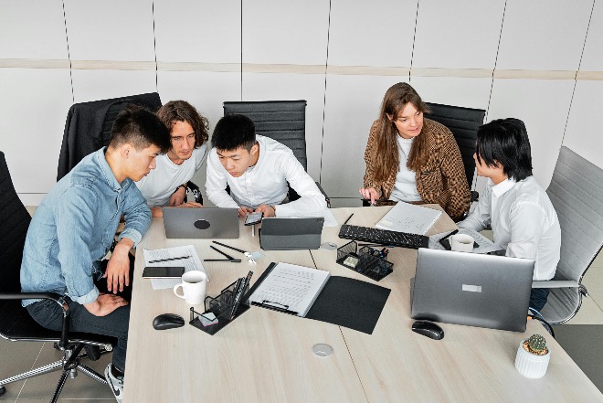International group of interns discussing work at a conference table