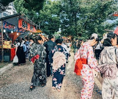 People in colorful yukata walking through a Japanese summer festival lined with food stalls