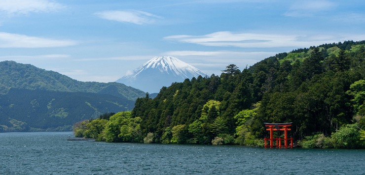 Red torii gate by Lake Ashi with Mount Fuji in the distance