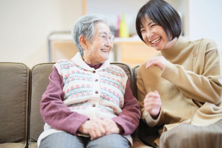 Elderly Japanese woman and young adult laughing and talking