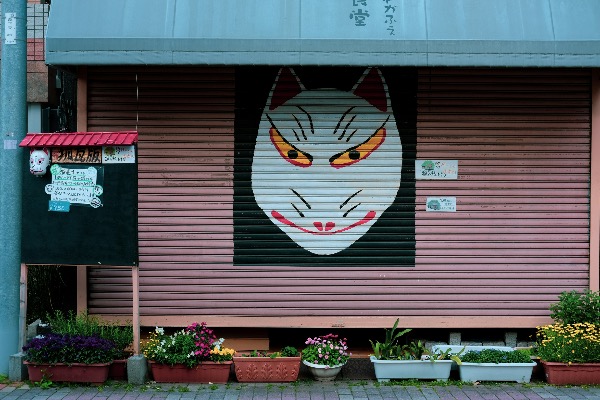 Traditional Japanese kitsune (fox) mask painted on a closed storefront shutter