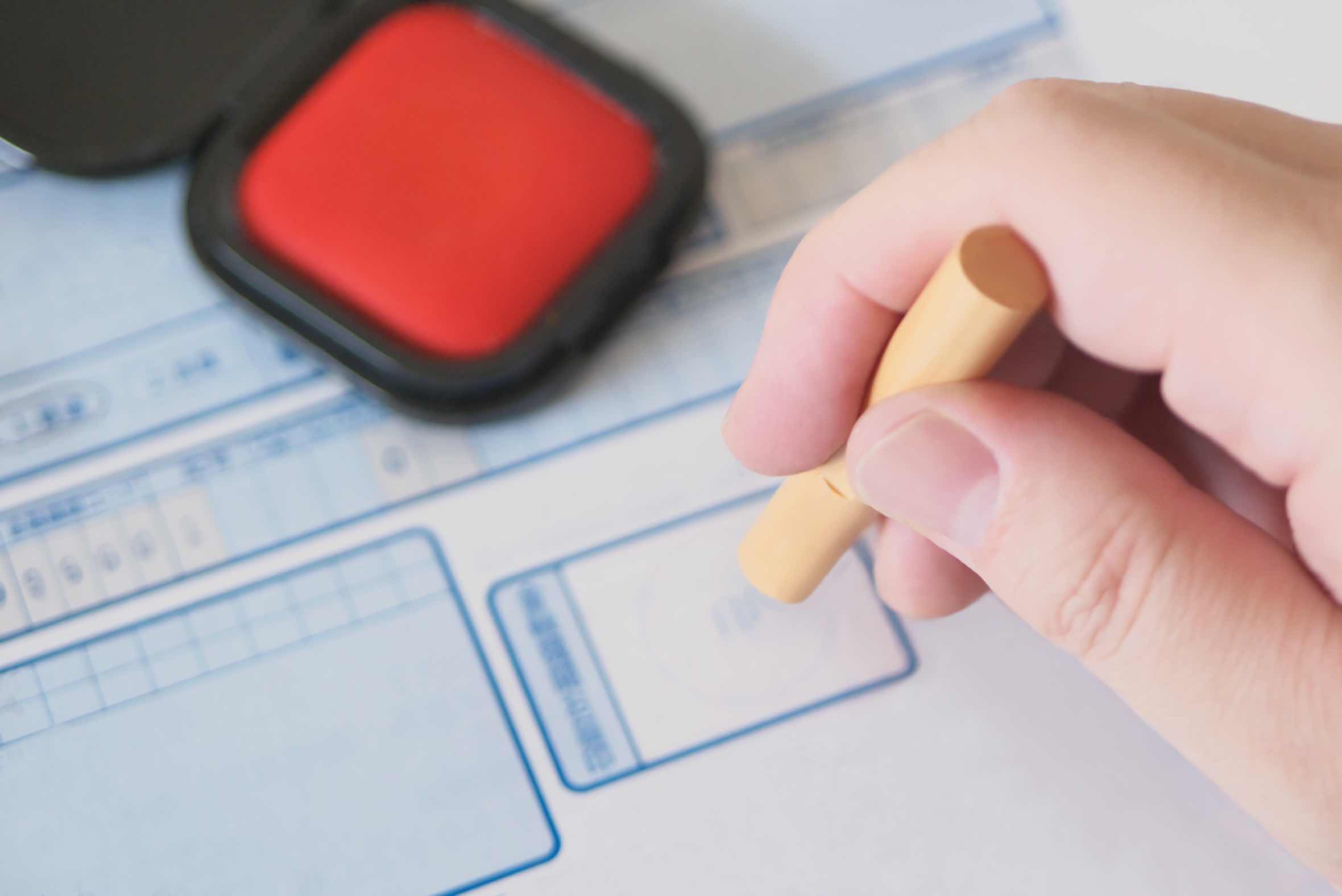 Hand using a personal hanko (Japanese seal) stamp on official documents