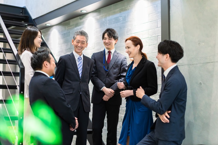 Japanese and international coworkers smiling and chatting in a relaxed setting.