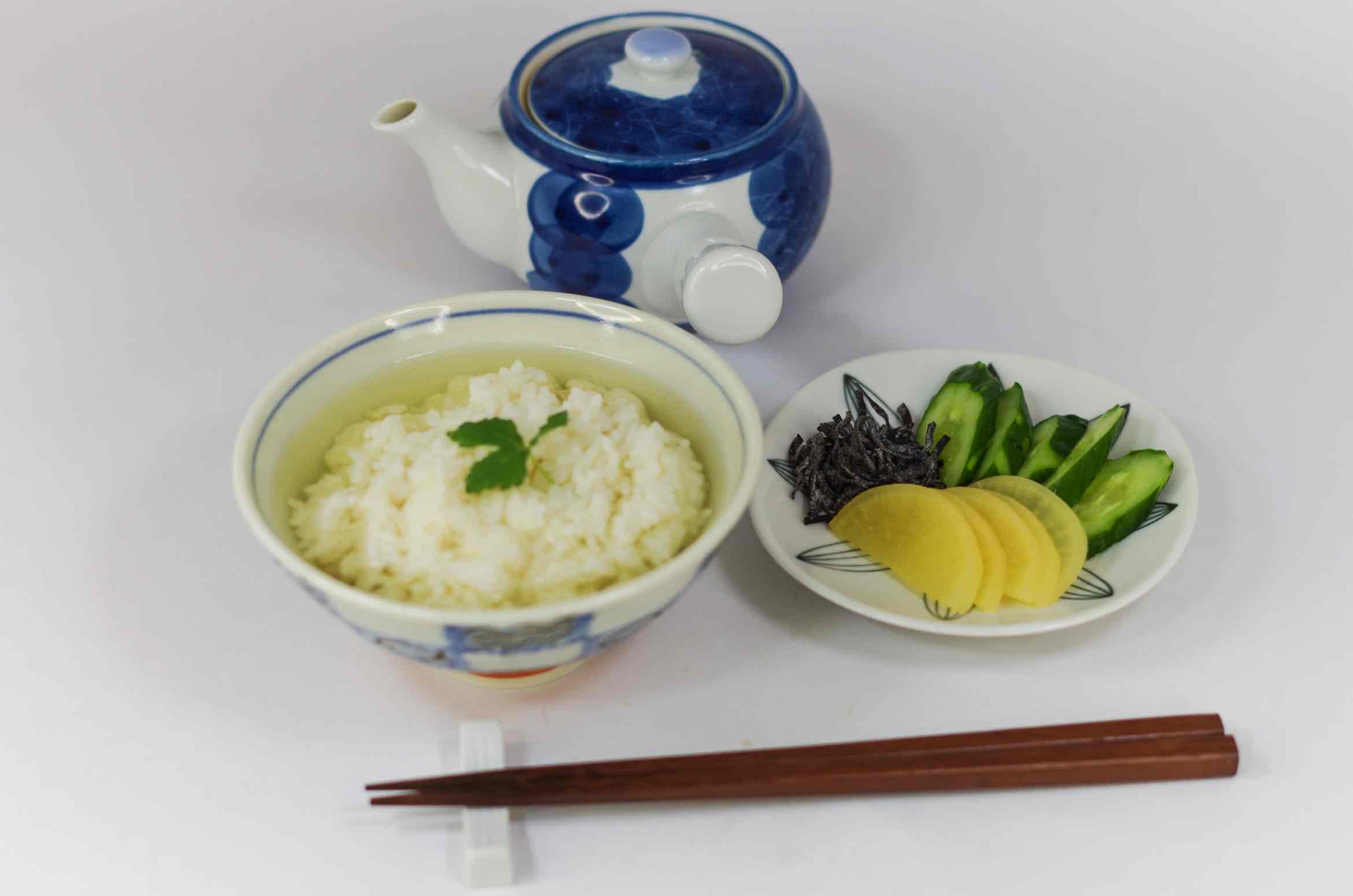A bowl of ochazuke: rice with tea poured over it, served with pickles and seaweed on the side.