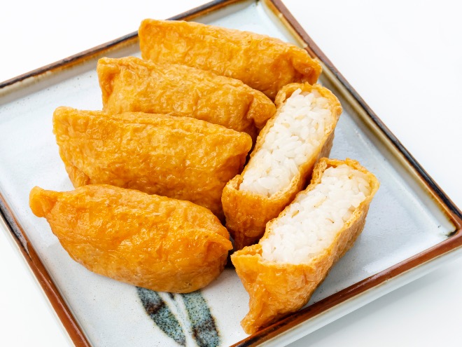 A plate of inarizushi: rice-stuffed tofu pouches with a sweet and savory flavor.