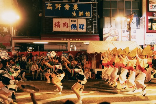 Performers in straw hats and yukata dance in the streets during Awa Odori, part of the Obon festivities.