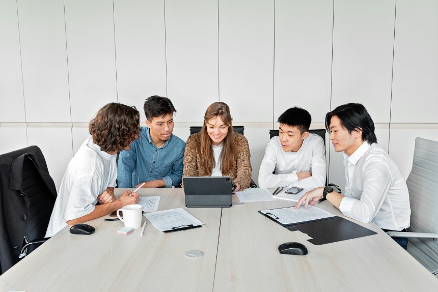 International interns in Japan working together on a group project, sharing ideas around a laptop.