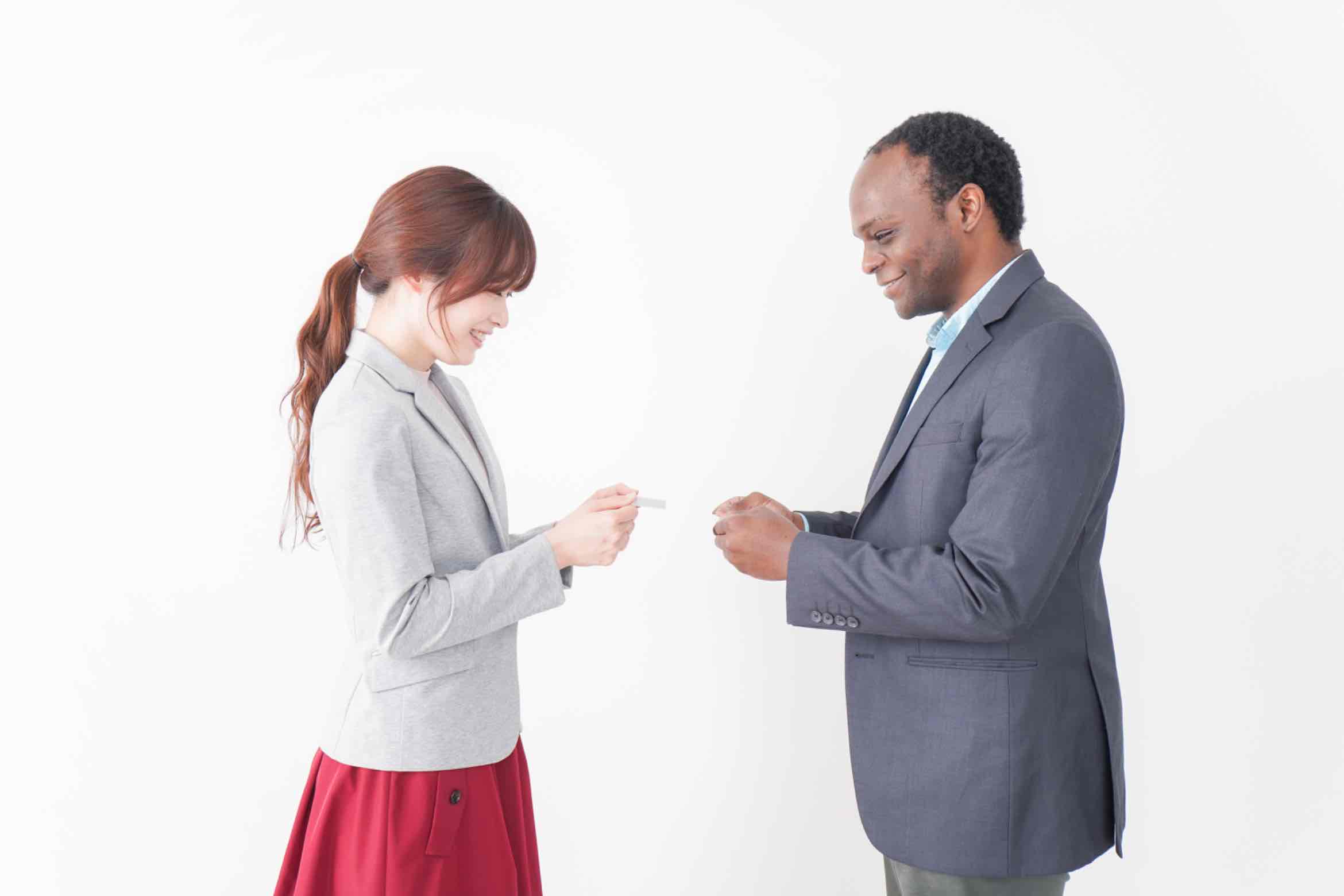 Two professionals, one Japanese and one international, smiling while exchanging Japanese business cards.