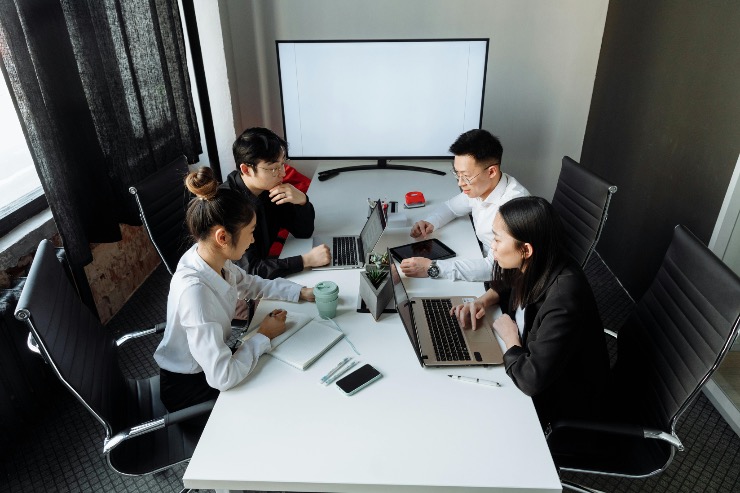 A group of professionals in Japan collaborating on laptops during a meeting, focusing on technology and data.
