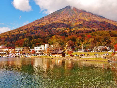 Autumn view of Lake Chūzenji and Mount Nantai in Nikkō covered with red and gold foliage.