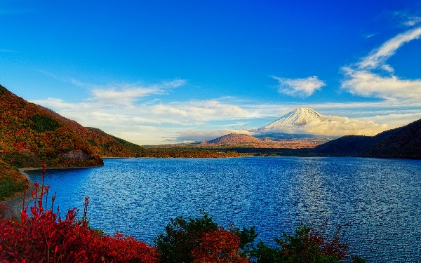 Mount Fuji and Lake Kawaguchi surrounded by autumn foliage under blue skies.
