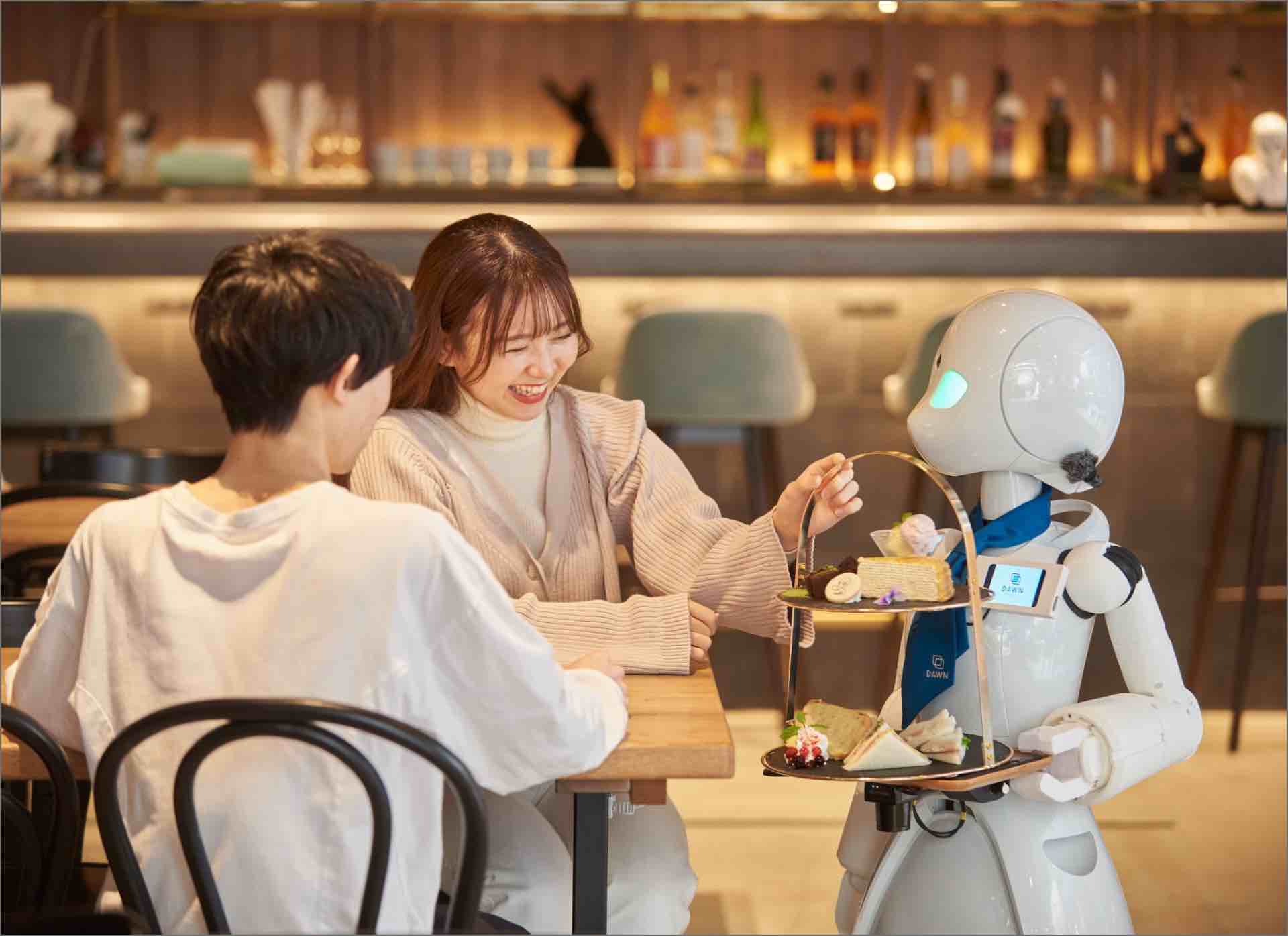 A robot serving food to smiling customers at a café in Tokyo, an example of technology supporting accessible employment.