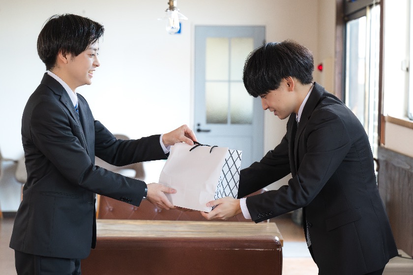 Two Japanese office workers exchanging a year-end gift as part of traditional business courtesy practices.