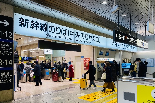 Travelers with luggage moving through a Japanese train station during the New Year holiday period.