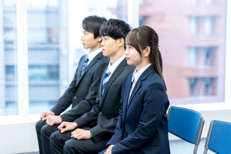 Three young Japanese business professionals seated during a formal recruitment meeting