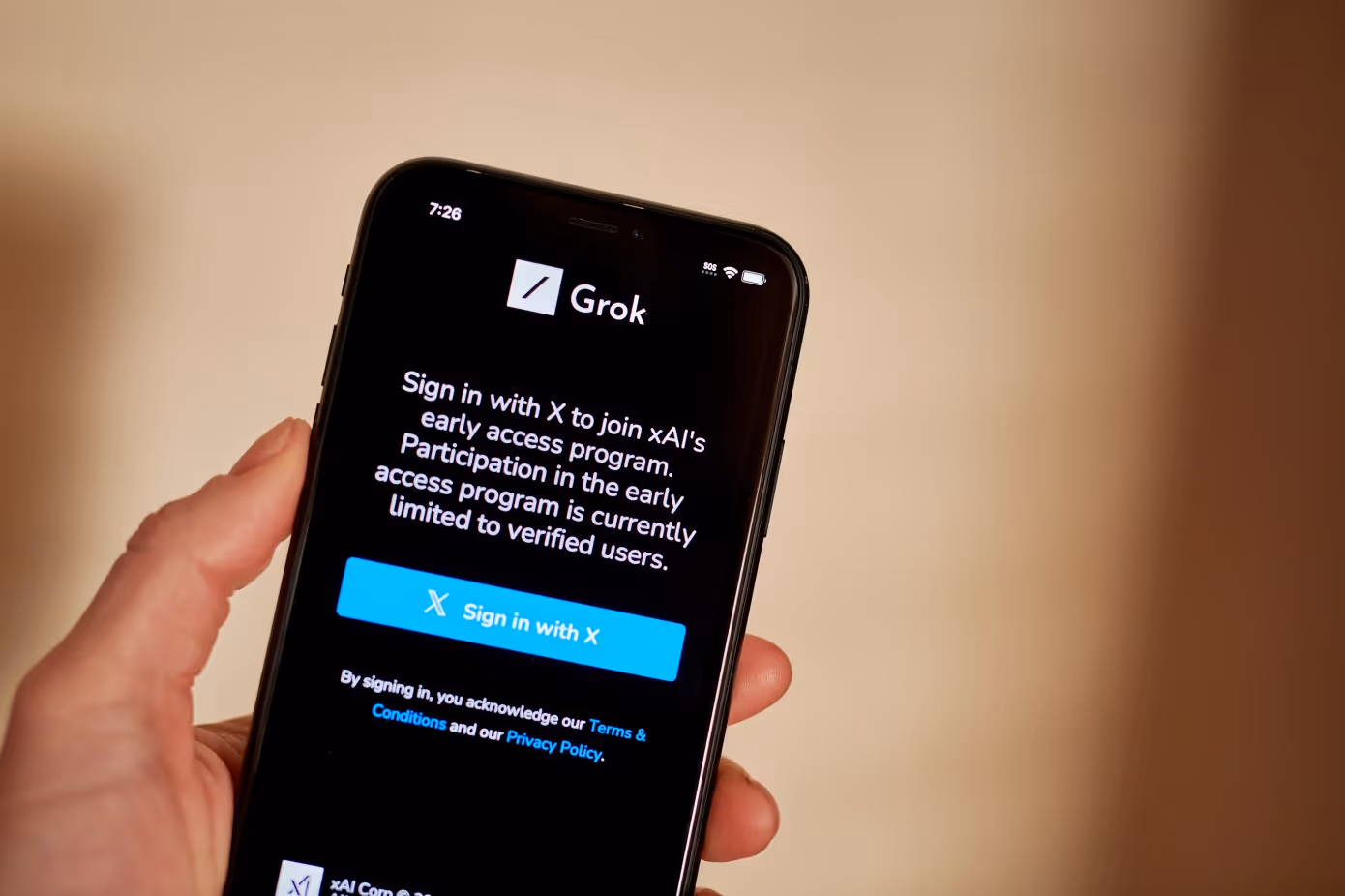Hand holding a mobile phone showing Grok sign-in screen
