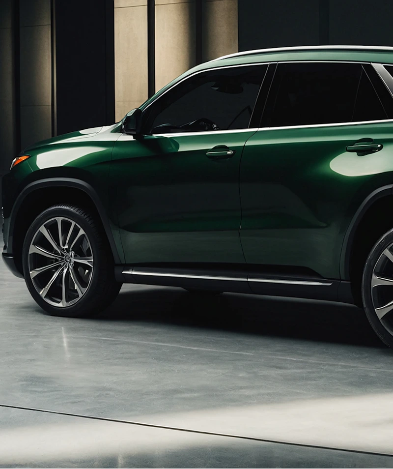 Side view of a dark green luxury SUV parked indoors with modern large alloy wheels.